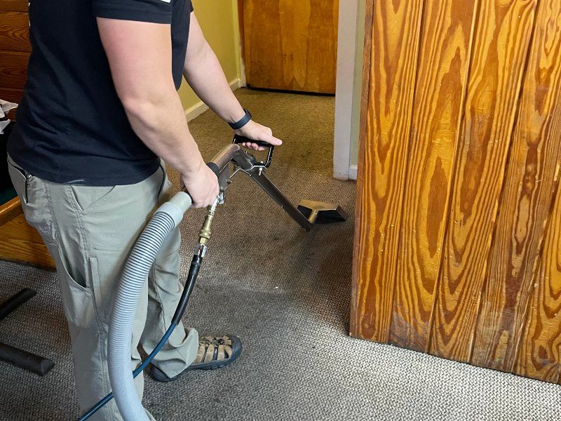 Sano Steam technician cleaning residential carpet in a hallway with hot water extraction wand