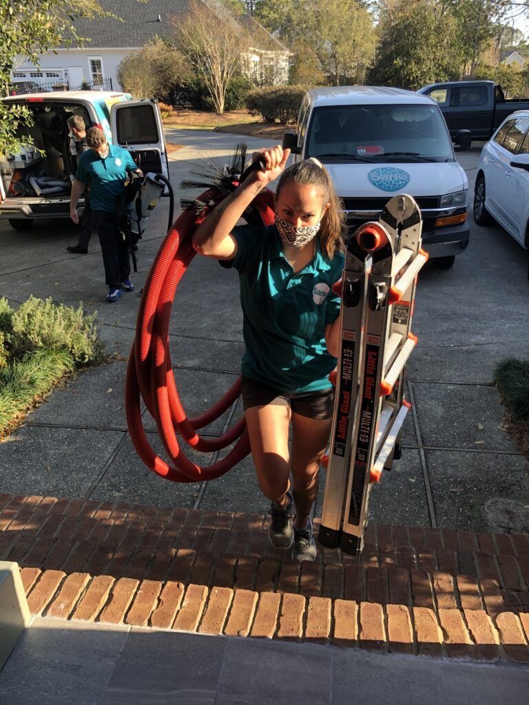 Sano Steam technician carrying professional duct cleaning equipment to a residential job site
