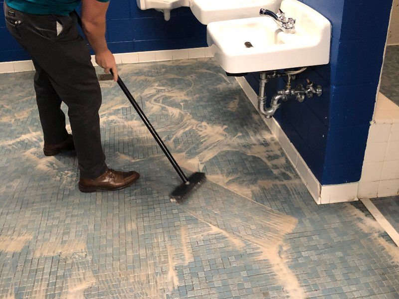 Sano Steam technician scrubbing commercial bathroom tile floor with cleaning solution