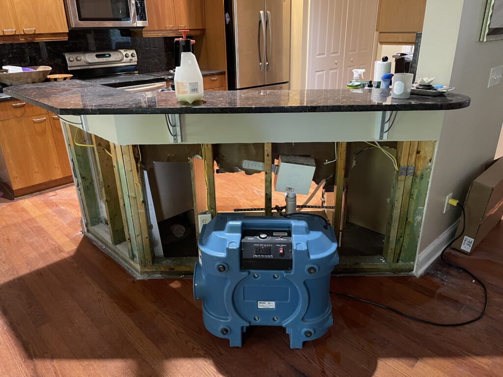 Professional air scrubber drying water damage under kitchen island with removed lower cabinets